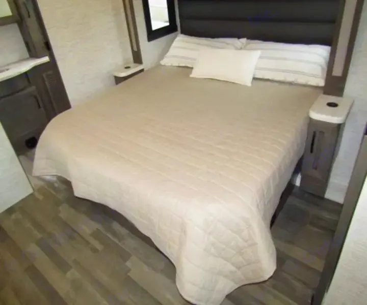 Cozy RV rental bedroom with a comfy bed, quilted bedspread, built-in nightstands, and wood-look flooring, perfect for your journey.. Jayco Precept 2025