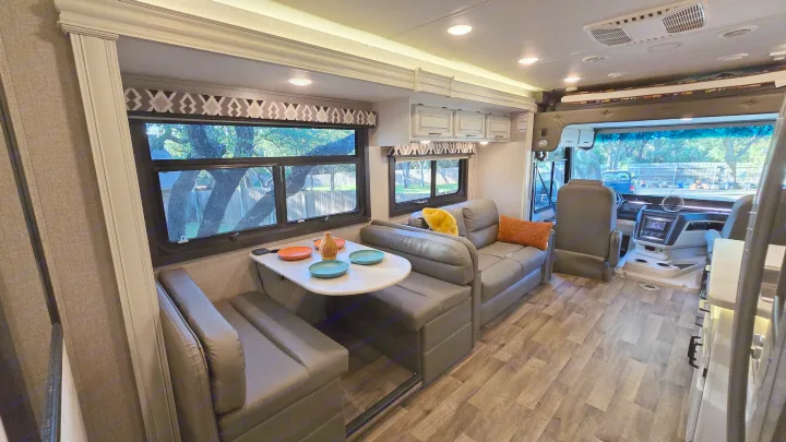 Modern RV rental interior with spacious dinette, comfortable sofa, and front driver's area.. Entegra Coach Vision XL 2021