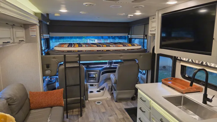 Spacious rv rental interior featuring a comfy bunk over the cab, kitchen, and living area, perfect for travel.. Entegra Coach Vision XL 2021
