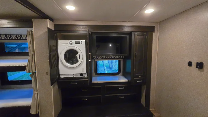 This **RV rental** interior features **bunk beds**, a **Splendide washer/dryer**, and an **entertainment center** for a comfortable **travel** experience.. Entegra Coach Vision XL 2021