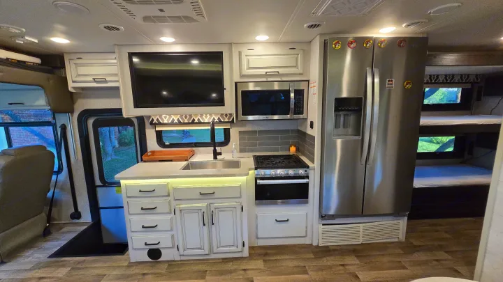 Step inside this modern RV rental! Features a full kitchen, large refrigerator, TV, and bunk beds, perfect for travel.. Entegra Coach Vision XL 2021
