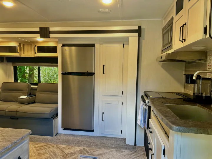 Bright and modern RV rental showcasing a full kitchen, stainless steel fridge, and comfortable sofa seating.. Forest River Palomino Puma XLE 2023