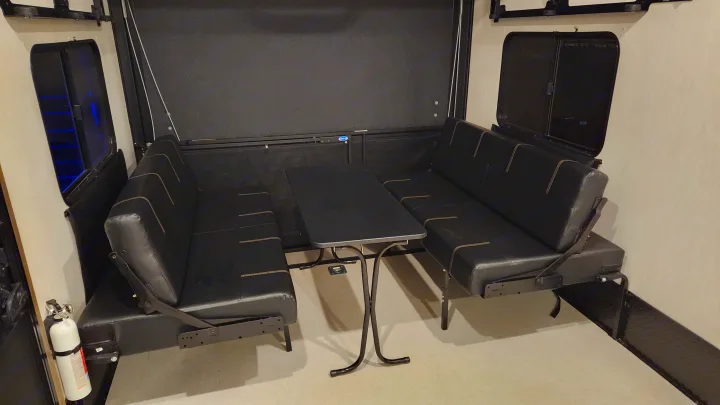 RV rental interior: A comfortable dinette with black convertible benches and a table for dining or lounging.. Forest River Vengeance Vengeance Rogue Amored Toy Hauler 2022