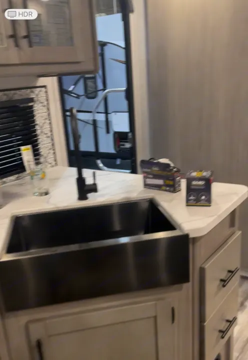 This RV rental features a stylish kitchen with a large black farmhouse sink, sleek faucet, and light cabinetry.. Dutchmen Coleman Light 2022
