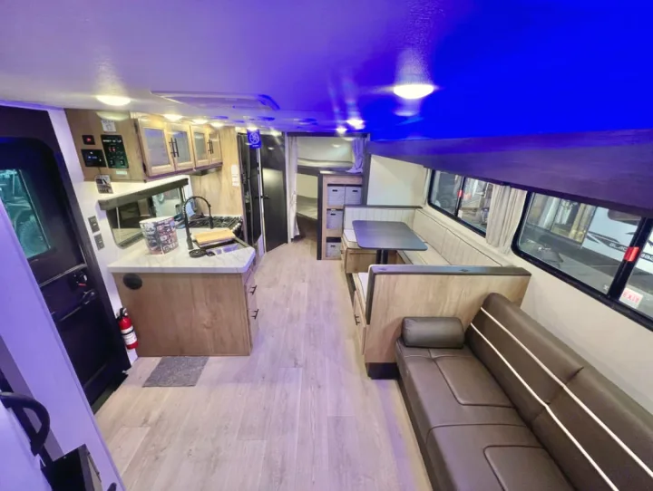 Inside this spacious RV rental: a kitchen, dinette, and sofa area, all illuminated by vibrant blue lighting.. Forest River Cherokee Grey Wolf 2026
