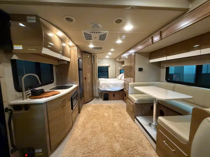 Spacious rv rental interior featuring a modern kitchen, comfortable dining booth, and rear bedroom area for travel comfort.. Entegra Coach Qwest 2019