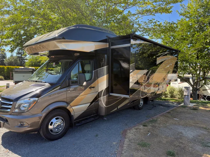 Luxury Entegra rv rental, a sleek motorhome with an extended slide-out and awning, parked at a sunny campsite.. Entegra Coach Qwest 2019