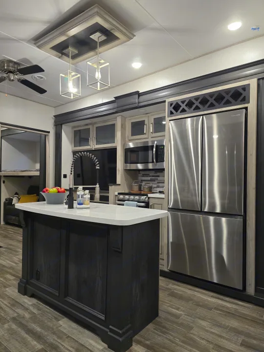 Modern RV rental kitchen interior with a spacious island, stainless steel appliances, and wood-look flooring.. Keystone RV Alpine Avalanche 2024
