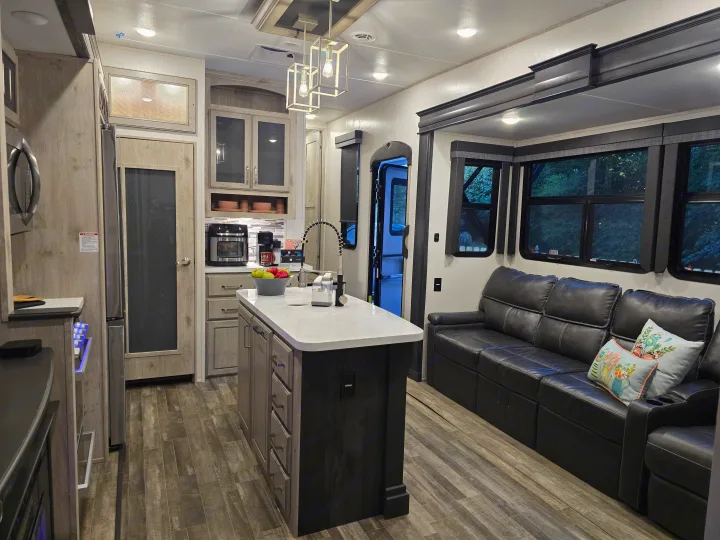 This modern RV rental features a full kitchen with an island and a comfortable living area with a leather sofa.. Keystone RV Alpine Avalanche 2024