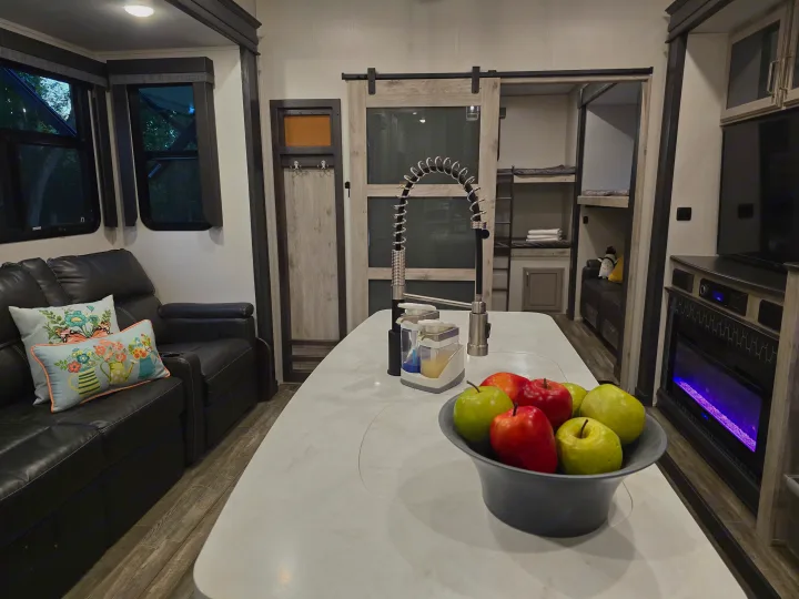 Spacious RV rental with a modern kitchen island, cozy living area, electric fireplace, and bunk beds. Ideal for trips.. Keystone RV Alpine Avalanche 2024