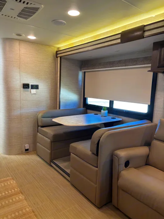 Spacious RV rental interior with a modern dinette, comfy seating, bright lighting, and large windows. Perfect for your next trip.. Entegra Coach Esteem 2021
