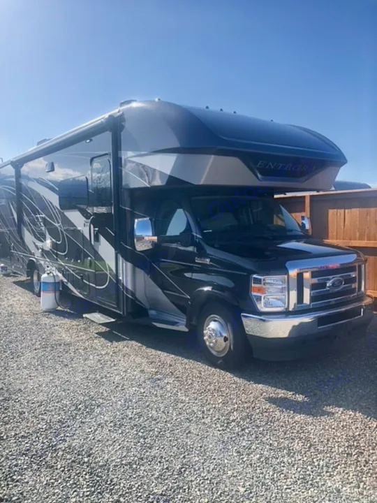 Spacious black & grey Entegra motorhome RV rental parked on gravel, ready for travel.. Entegra Coach Esteem 2021