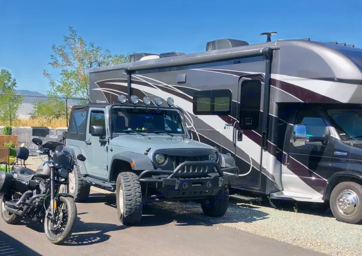 RV rental adventure: Motorhome, Jeep, and motorcycle ready for exploration on a sunny day.. Entegra Coach Esteem 2021
