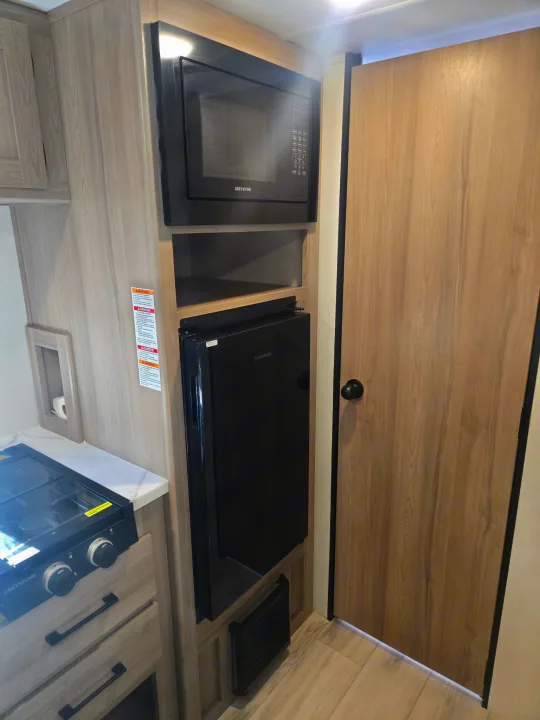 RV rental: Modern kitchen setup with Greystone microwave, Furrion fridge, and stove, surrounded by light wood cabinets.. Keystone Colman 2025
