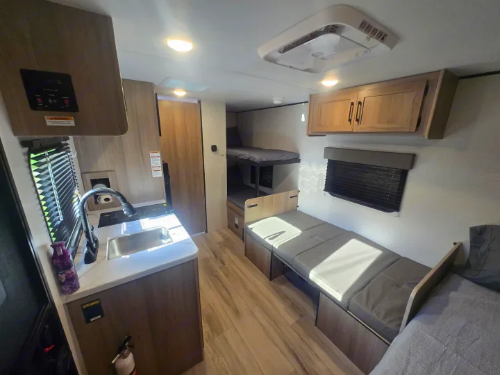 Modern RV rental interior showcasing a full kitchen, bunk beds, comfy dinette, and a cozy sleeping area.. Keystone Colman 2025