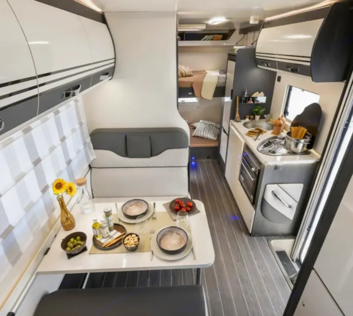 This bright RV rental interior showcases a dining area, compact kitchen, and bunk beds, perfect for comfortable travel adventures.. ROLLERTEAM ZEFIRO 675 2026