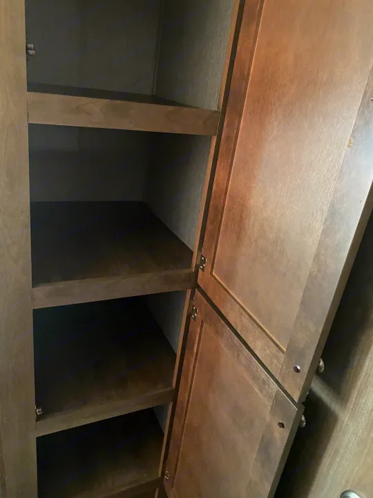 Inside an RV rental: Open wooden cabinet with multiple empty shelves for convenient storage.. Dutchmen Coleman Lantern LT 2020