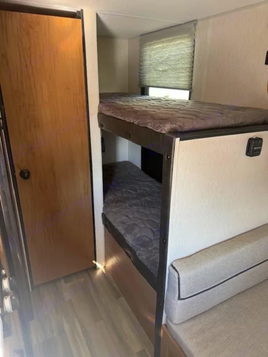 This RV rental features cozy bunk beds, a window, and seating, optimizing space for travel.. Cherokee WOLF PUP  16BHSBL 2023