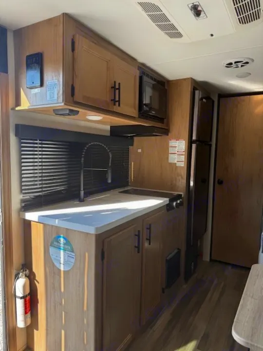 RV rental interior: A well-equipped kitchen with light wood cabinets, microwave, sink, stovetop, and refrigerator.. Cherokee WOLF PUP  16BHSBL 2023