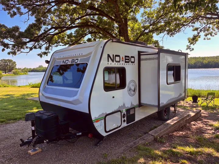 Enjoying a serene lakefront RV rental experience with this No Boundaries travel trailer, perfect for outdoor adventures.. No Boundaries 19 2021