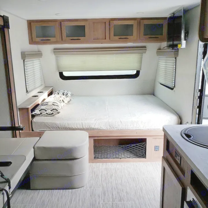 This RV rental showcases a cozy bedroom with overhead storage, compact kitchen, and seating area, perfect for travel comfort.. No Boundaries 19 2021