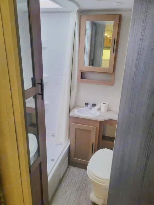 Compact RV rental bathroom: features shower, sink vanity, mirrored cabinet, and toilet. Ideal for travel.. No Boundaries 19 2021
