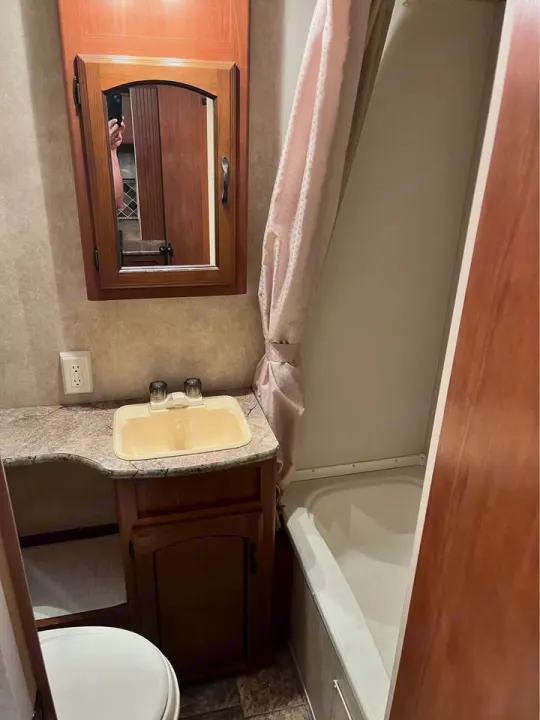Inside an RV rental: a compact bathroom with a sink, medicine cabinet, toilet, and small tub/shower, optimized for travel.. Forest River Wildwood X-Lite 2013