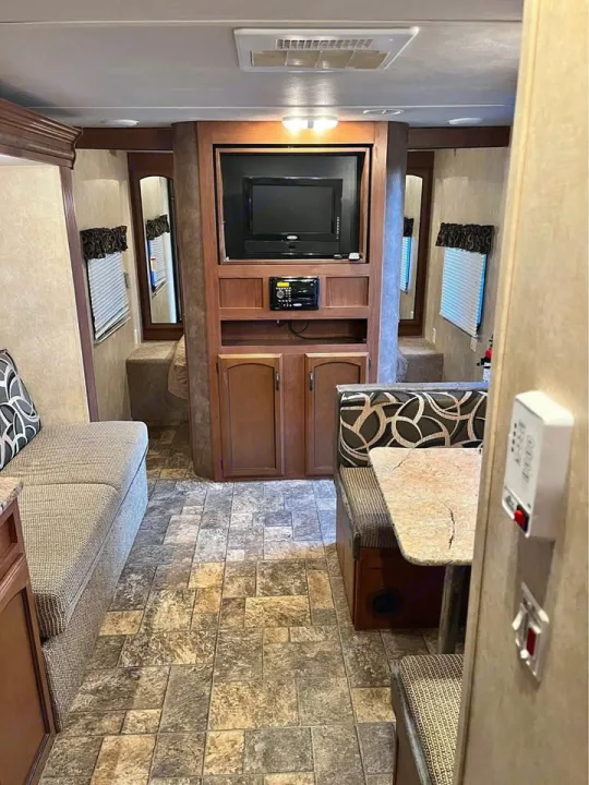 Cozy RV rental interior featuring a dinette, bench seating, and an entertainment system for comfortable travel.. Forest River Wildwood X-Lite 2013