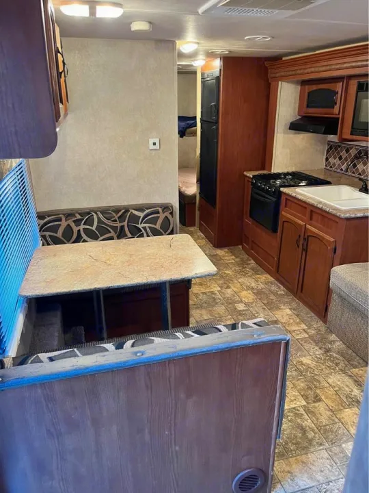 Experience comfort in this RV rental's interior, featuring a dinette, kitchen, and hallway leading to a sleeping area.. Forest River Wildwood X-Lite 2013