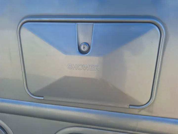 RV rental outdoor shower access panel with key lock, useful for convenient water access outside the vehicle.. Nexus Phantom 2024