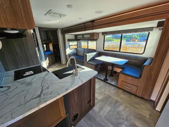 Inside a sleek RV rental: modern kitchen, spacious dinette, and comfortable living area with large windows.. Dutchmen Kodiak Ultra Lite 2021