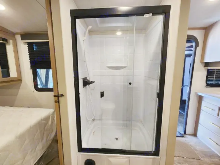 Step inside this RV rental's bathroom, featuring a compact, glass-enclosed shower stall with a white interior.. Keystone RV Outback Ultra Lite 2024
