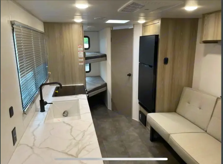 RV rental: modern kitchen with sink, bunk beds, refrigerator, and sofa. Bright interior, perfect for family adventures.. Forest River Salem Cruise Lite 2024