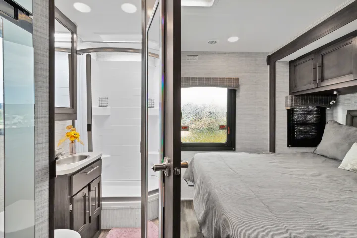 This RV rental features a well-appointed bedroom and a compact bathroom with a shower, sink, and toilet.. Jayco Redhawk SE 2024