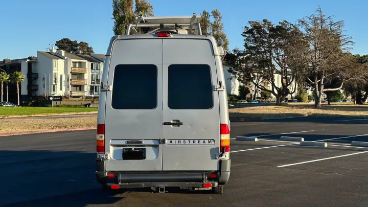 Silver Airstream RV rental van with solar panels, parked outdoors. Ready for your next road trip adventure.. Airstream Interatate 2003