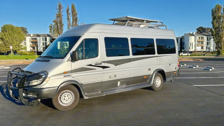 Silver Airstream camper van, a perfect rv rental choice. Features roof solar panels & front brush guard.. Airstream Interatate 2003