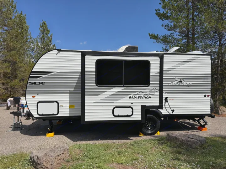 This Jay Flight Baja Edition travel trailer RV rental, parked amidst trees under a blue sky, is ideal for your next camping trip.. Jayco Jay Flight 2026