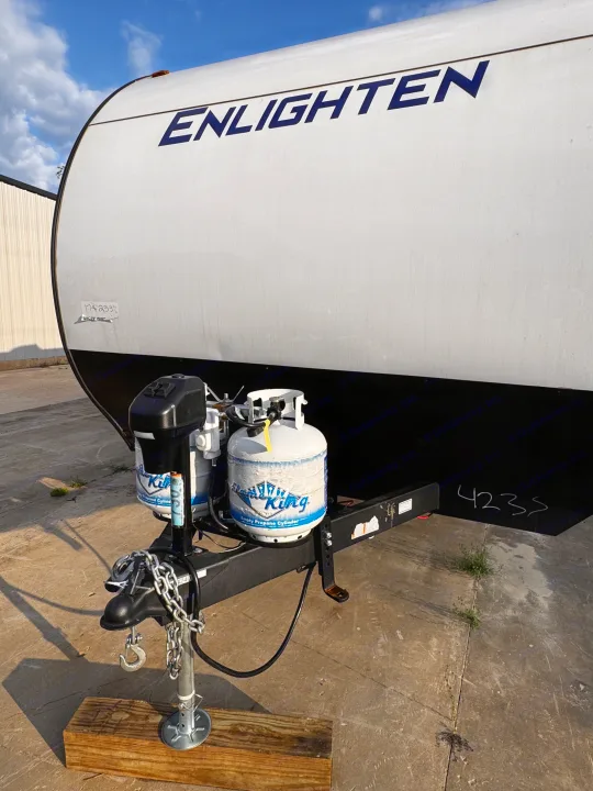 Front view of a white Enlighten travel trailer RV rental, equipped with dual propane tanks and a robust hitch.. Gulf Stream Enlighten 2025