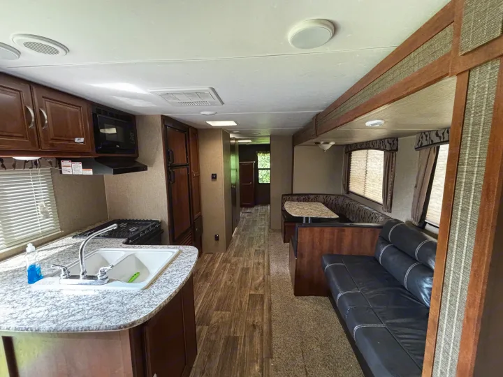 RV rental interior: fully equipped kitchen, U-shaped dinette, and sofa. Hallway leads to the rear.. Keystone RV Passport Grand Touring 2016