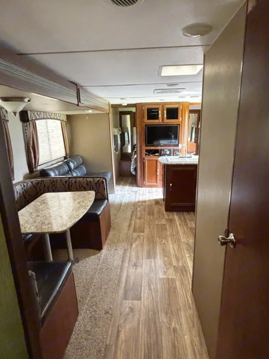 Explore this RV rental's spacious interior with a dinette, full kitchen, and hallway leading to a bedroom area.. Keystone RV Passport Grand Touring 2016