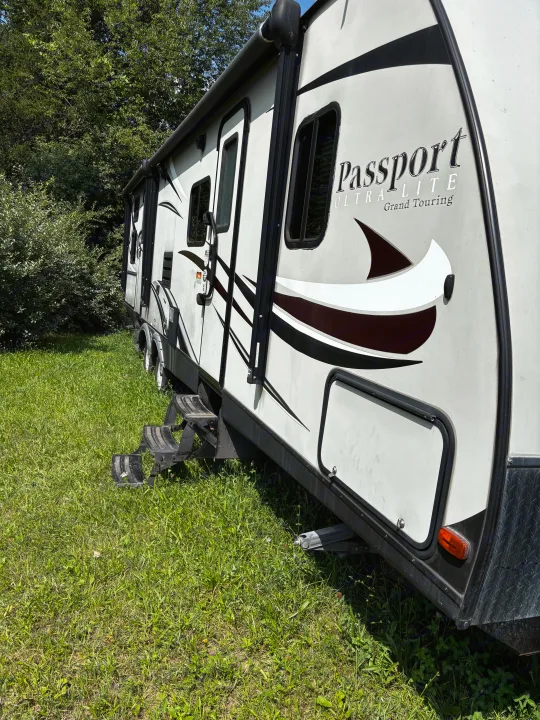 Passport travel trailer **RV rental** parked in green grass, inviting outdoor adventure and nature escapes.. Keystone RV Passport Grand Touring 2016