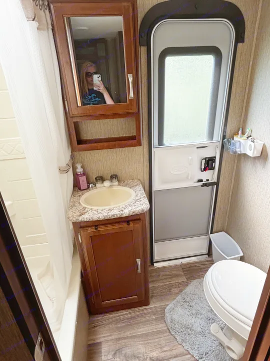 Compact RV rental bathroom: sink, mirrored cabinet, shower, and toilet near the entry door. Functional interior space.. Keystone RV Passport Grand Touring 2016