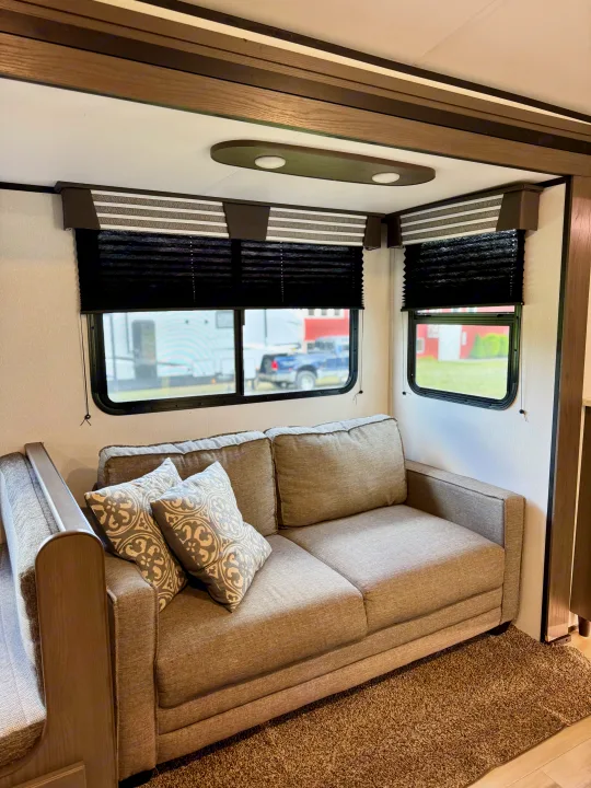 Cozy RV rental living area with a comfy sofa, patterned pillows, and modern window blinds, perfect for relaxation.. Cruiser RV MPG Ultra Lite 2022