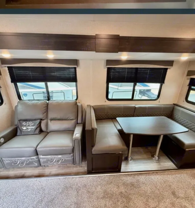 RV rental interior: cozy living area with reclining sofa & U-shaped dinette. Perfect for relaxing and dining on your trip.. Highland Ridge RV Range Lite 2021