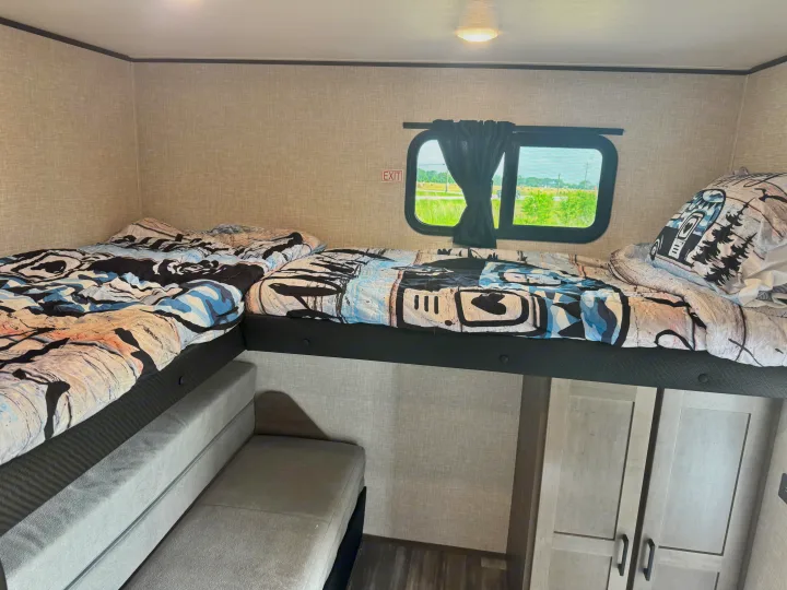 Cozy RV rental bunk bed setup with two beds, a convertible sofa below, window view, and storage.. Jayco Jay Jay Flight 294QBS 2025