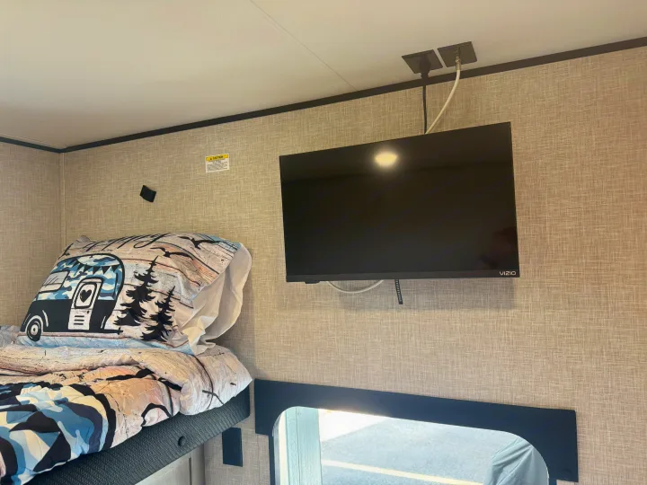 An RV rental interior showing a bunk bed with a playful duvet and a wall-mounted Vizio TV, neatly wired from the ceiling.. Jayco Jay Jay Flight 294QBS 2025