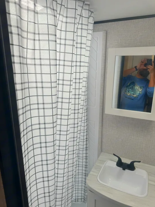 RV rental bathroom: White plaid shower curtain, sink, and mirror view inside a compact RV.. Jayco Jay Jay Flight 294QBS 2025