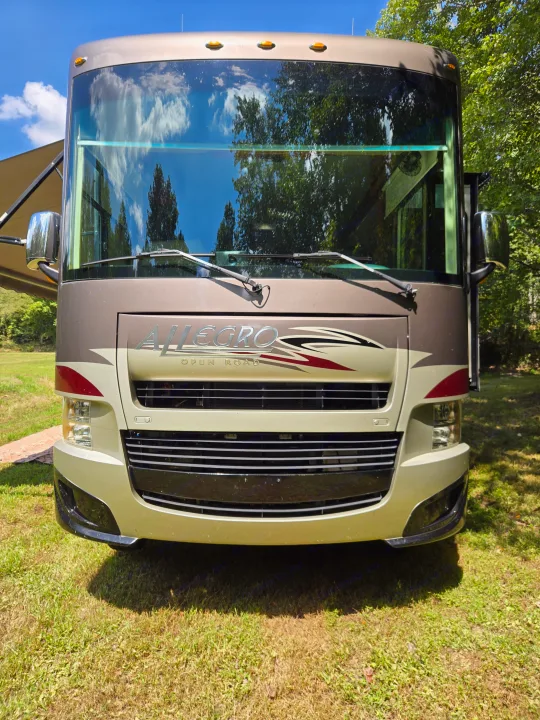 Front view of an Allegro Open Road RV rental parked on a sunny day in a grassy area with trees.. Allegro Allegro Motorhome 2014