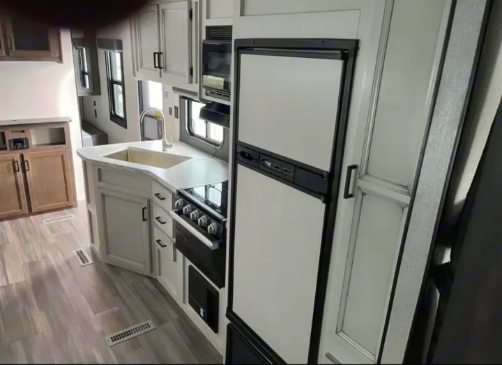Modern RV rental interior features a spacious kitchen with fridge, stove, microwave, and a cozy living area.. Highland Ridge RV Open Range 2022
