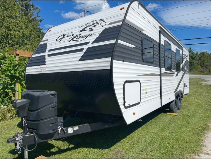 A sleek white & black Open Range travel trailer, parked on grass, ideal for your next rv rental and adventure.. Highland Ridge RV Open Range 2022